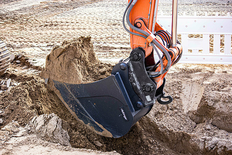 Standard Backhoe Bucket without Teeth (11 to 40 t) by Rädlinger filled with soil