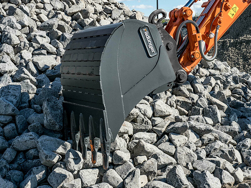 Backhoe Bucket X-TREME from a lateral perspective entering a pile of stones