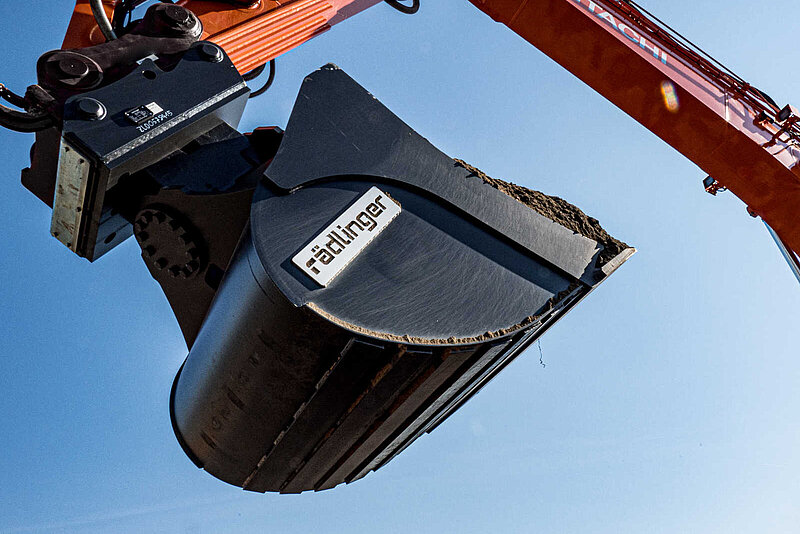 Backhoe Bucket with Tilt Motor filled with soil