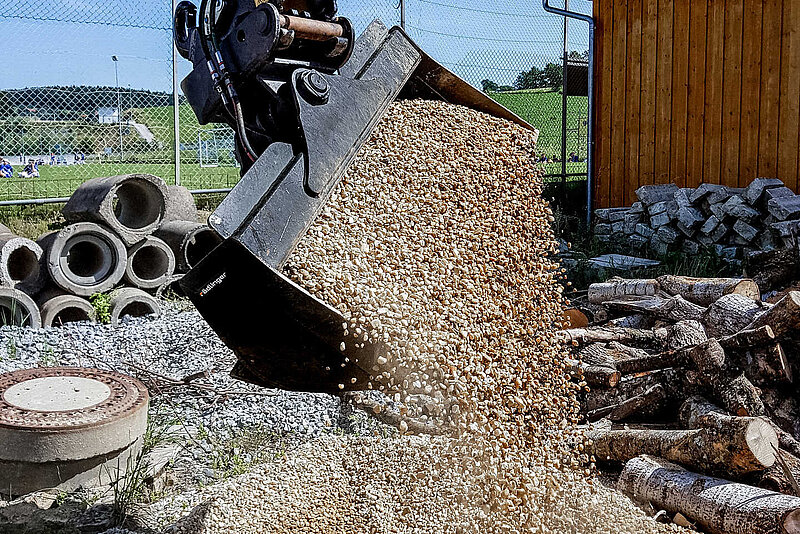 Pouring gravel finely dosed with the Ditch Cleaning Bucket with Cylinder (6 to 12 t) by Rädlinger